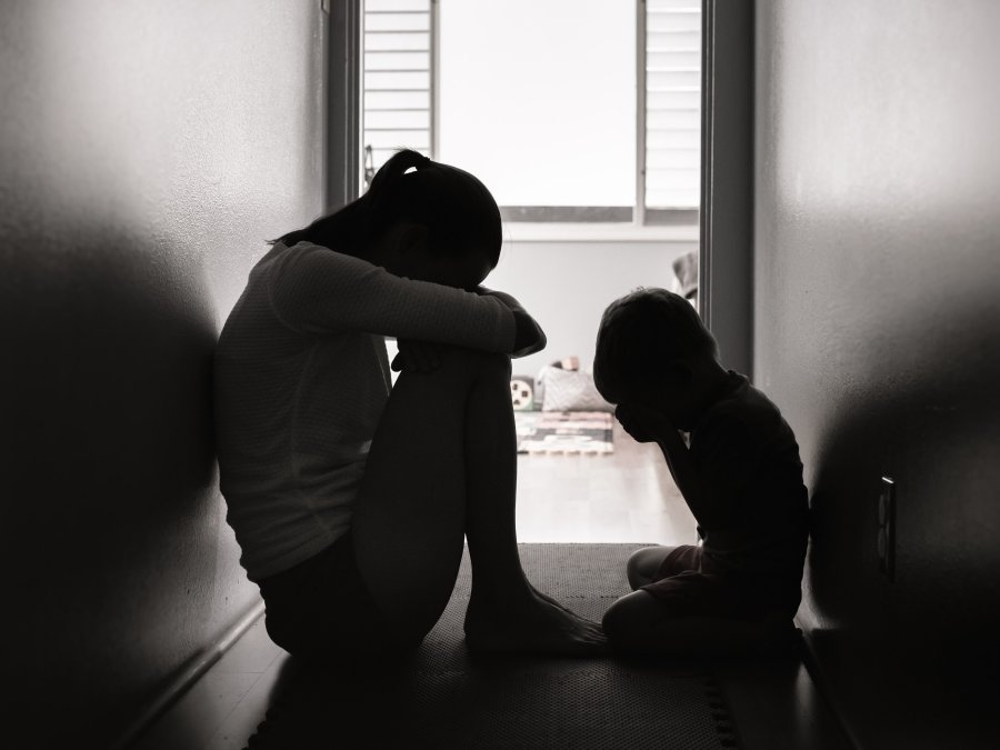 Black and white image of a sad mother and child sitting on the floor.