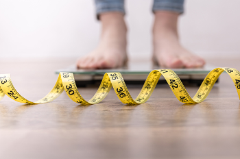 A photograph of a measuring tape in front of a two feet on a scale. Photo by Getty Images