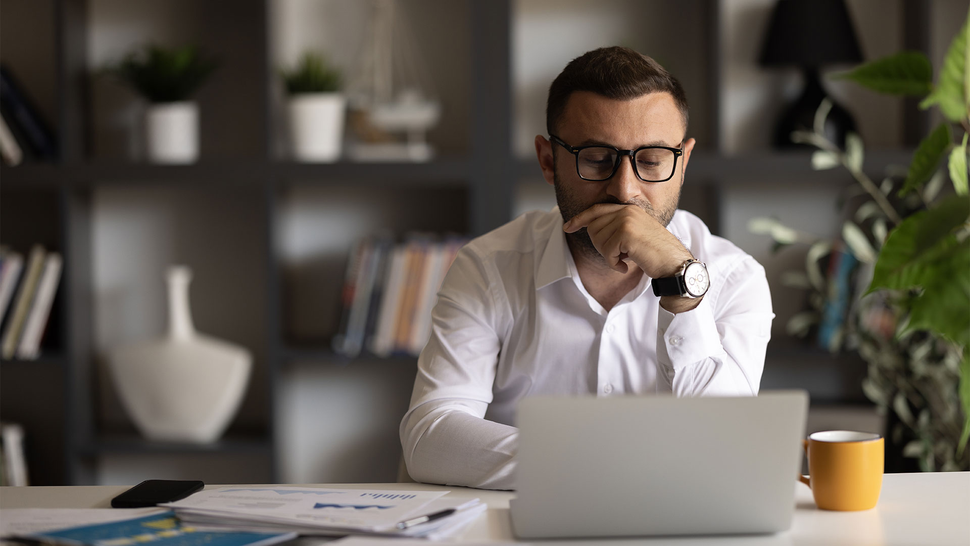 Man wearing glasses staring at a computer screen in an office