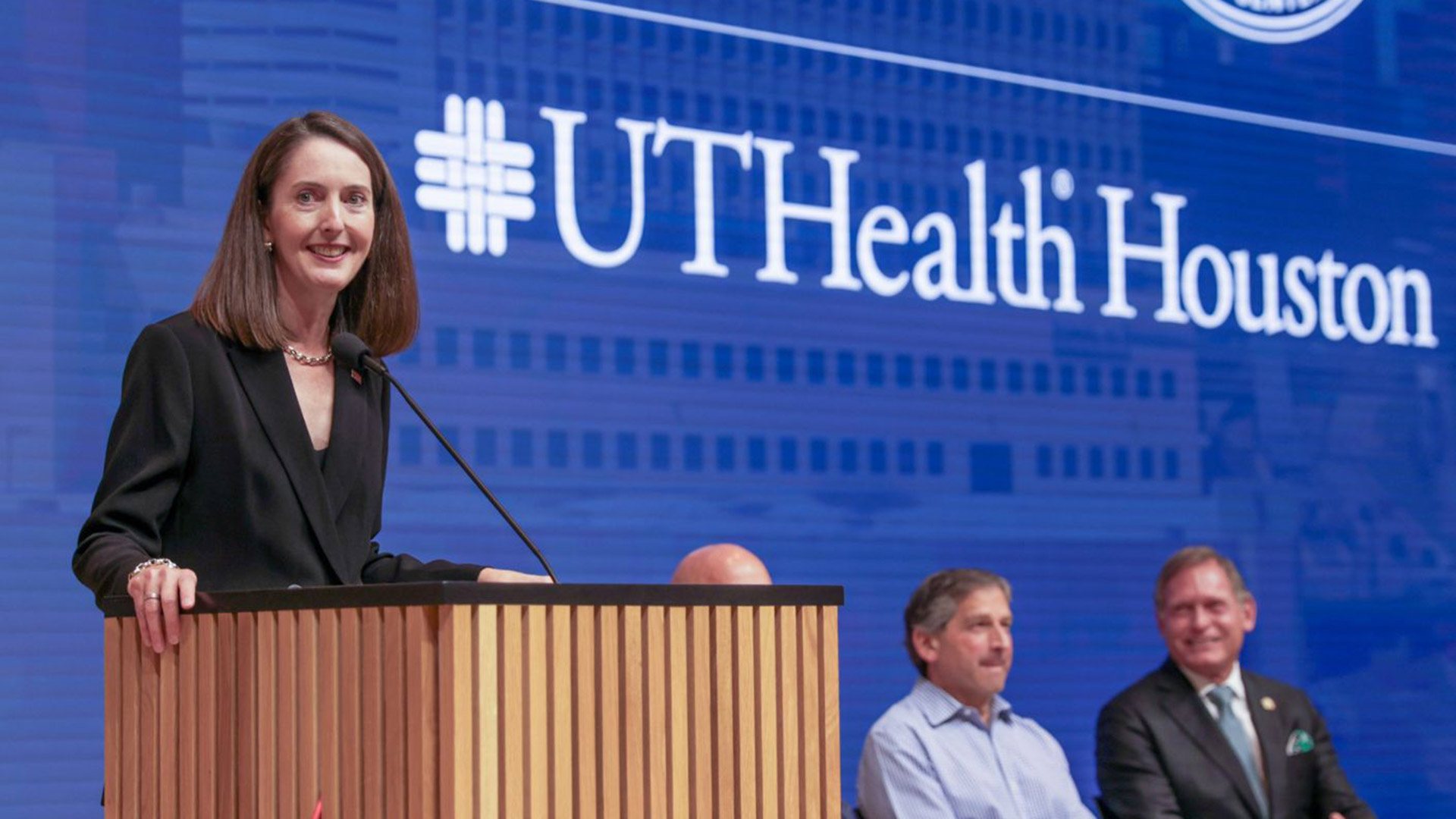 President Kibbe speaks at a podium during a UTHealth Houston event, with the university logo displayed behind her.