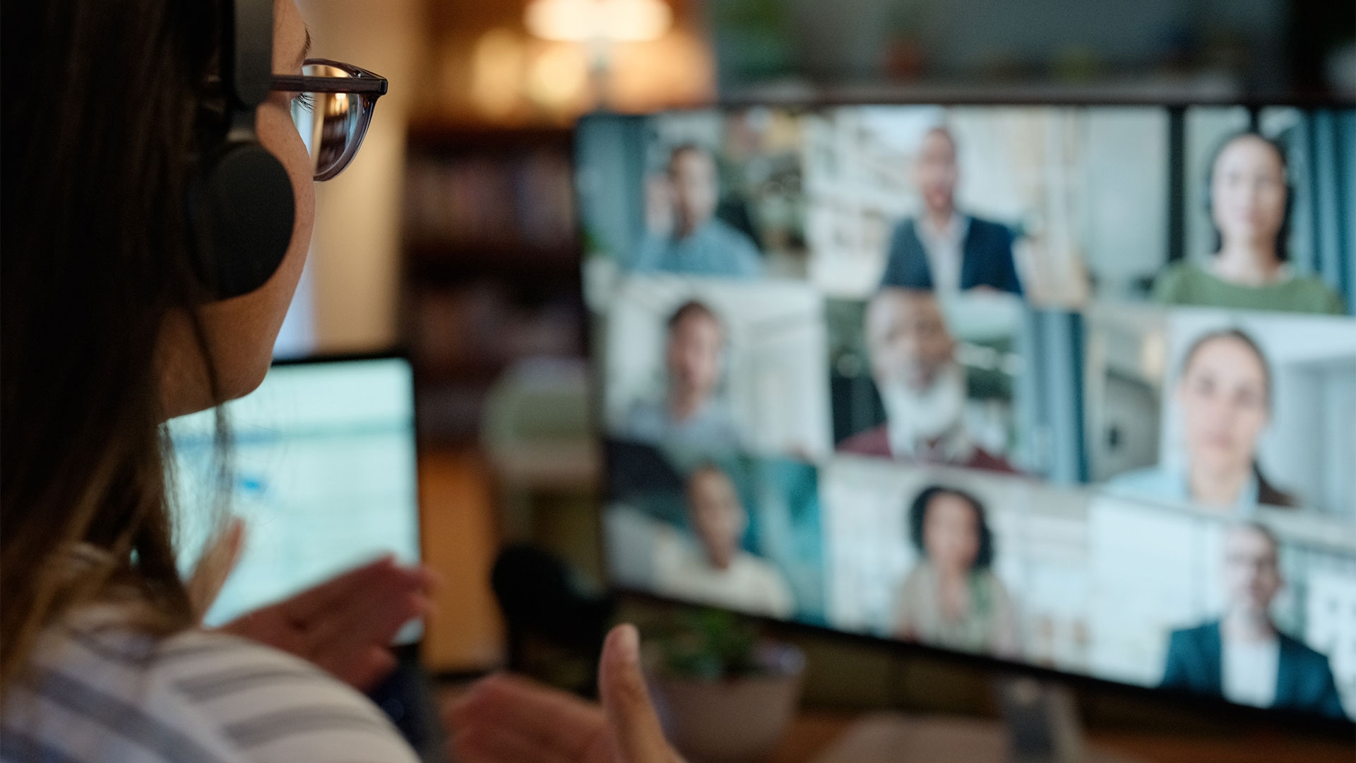 Woman wearing headphones and glasses in a online team meeting