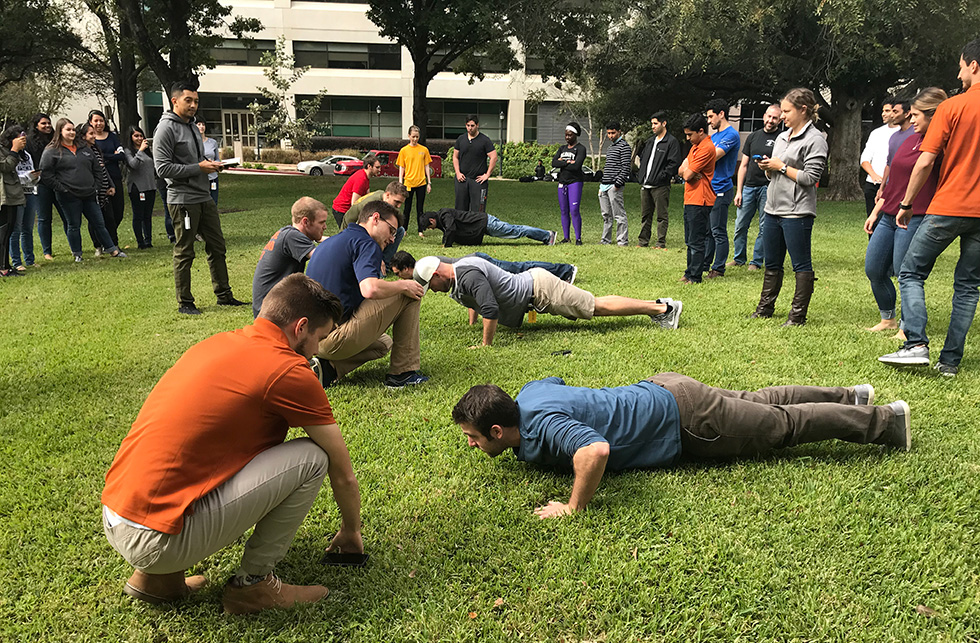 Participants engage in a friendly push-up competition on campus lawn as part of a wellness or team-building event.