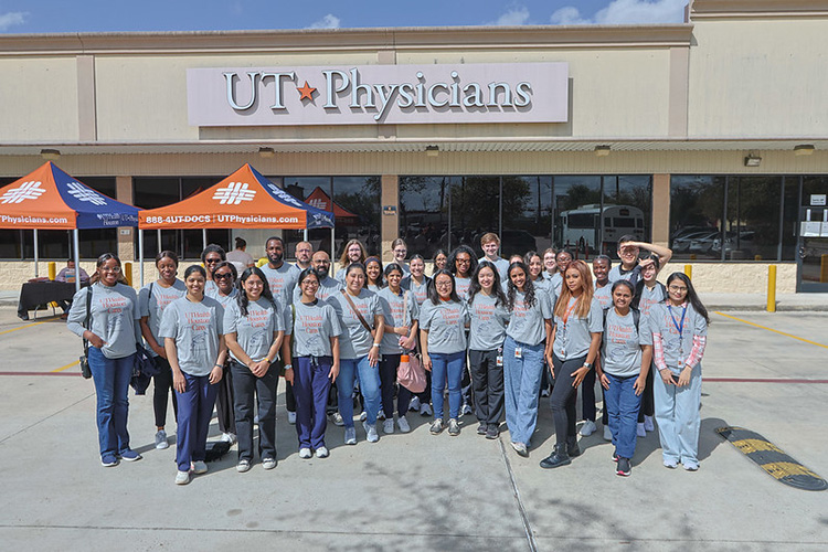 UTHealth students and staff pose for a group photo outside UT Physicians clinic during a community health fair event.